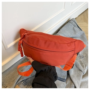 Detail of orange nylon waist bag showing dual zippers and braided decorative pullers