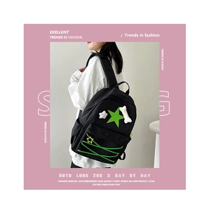 Detail of black nylon backpack with green star patch and bone pendant on model