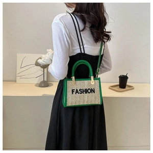 Détail d'un sac en paille tressée avec bordure en similicuir vert et broderie