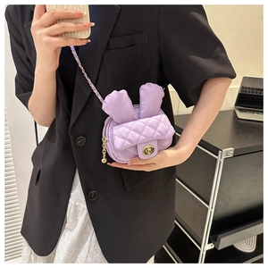 Detail of purple quilted mini bag with rabbit ears and golden twist lock on a shoulder strap