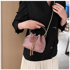 Close-up of pink rhinestone bucket bag with golden ring handle and fringe details