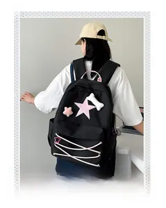 Close-up of black backpack featuring pink star patches, lacing, and bone charm detail
