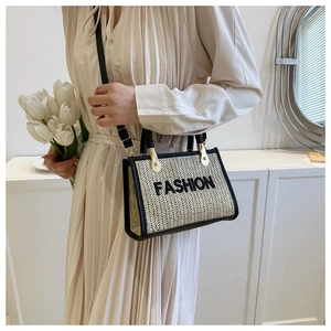 Détail d'un sac bandoulière en paille beige avec bordures en cuir noir et broderie Fashion