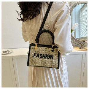 Mannequin portant un sac bandoulière en paille tressée avec des finitions en cuir noir