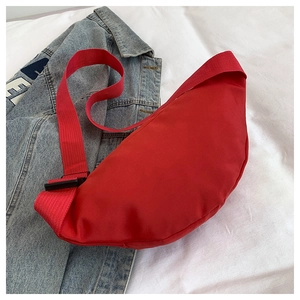 Detail of red crescent nylon shoulder bag on a blue denim jacket background