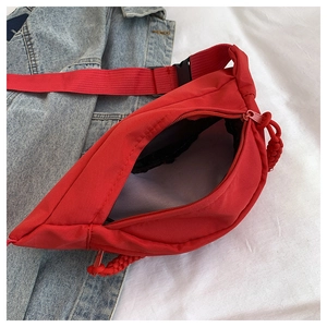Detailed top view of red nylon crossbody bag with zipper and inner lining on white fabric