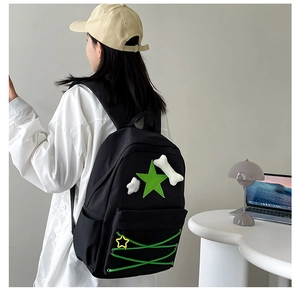Detail of black nylon star backpack with green ribbon lacing and plush bone charms