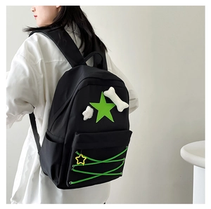 Detail of black star backpack with green cross straps and white bone plush charms