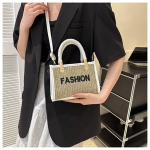 Détail du sac bandoulière en paille avec broderie FASHION noire et finitions en cuir blanc