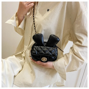 Detail showing mini black quilted crossbody bag with rabbit ear design and gold chain strap
