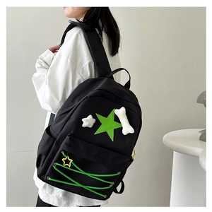 Detail of black backpack with green star patch and plush bone pendant on shoulder strap