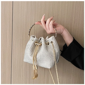 Close-up of sparkling silver rhinestone bucket bag with metal handle and drawstring tassel