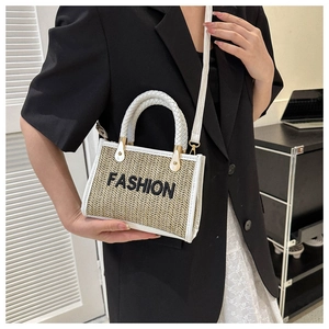 Détail du sac bandoulière en paille tressée avec garniture en cuir blanc et broderie