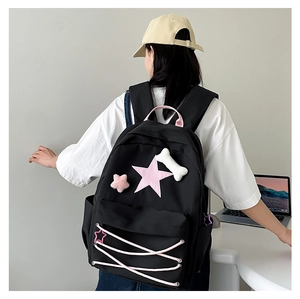 Detail of black school backpack with pink star and plush bone charm for teenage girls