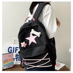 Close-up of black school backpack featuring pink star patch and ribbon lace detailing