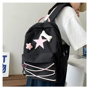 Close-up of black Y2K backpack featuring pink star patches and decorative crisscross drawstrings