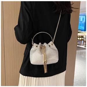 Detail showing sparkling rhinestone bucket bag with golden ring handle and elegant tassels