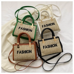 Détail de sacs en paille tressée montrant la broderie et la quincaillerie en métal doré