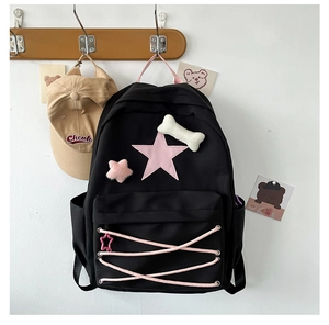 Detail of cute black star backpack with pink leather star and plush bone charm