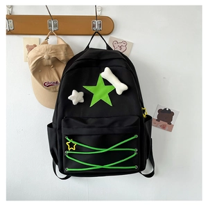 Detail of black canvas backpack with green star patch and cute plush bone pendant