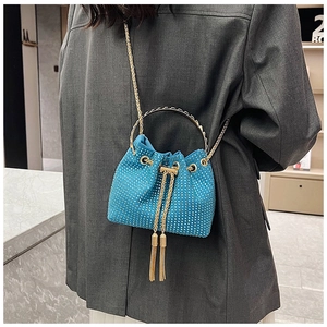 Detail of electric blue rhinestone bucket bag with gold ring handle and metal tassels