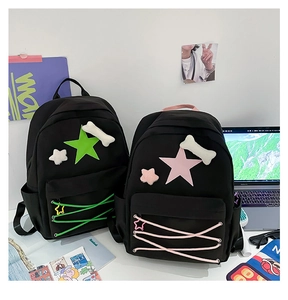 Detail of black nylon student backpacks with green and pink star motifs on a desk