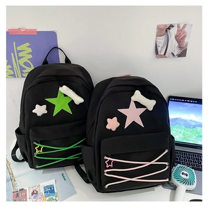 Close-up of black canvas star backpack with plush bone charm in a student desktop setting