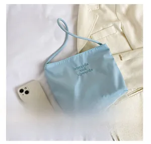 Detail view of a light blue nylon crossbody bag with a white smartphone for scale