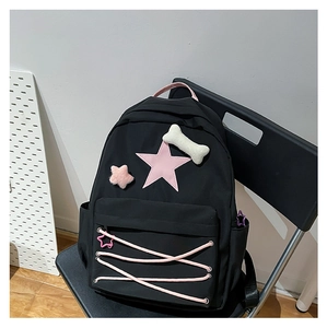 Detail of black nylon star backpack with pink criss-cross drawstring and plush charms