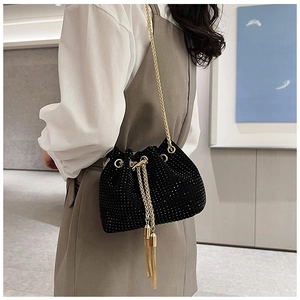 Detail of black rhinestone bucket bag with golden chain strap and tassel drawstring