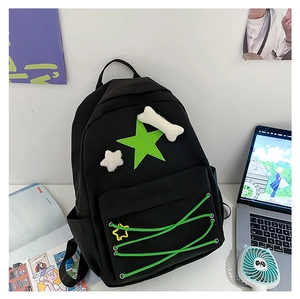 Close-up of black school backpack with green star patch and cute plush bone pendant