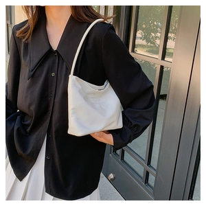 Detailed close-up of cream white nylon shoulder bag with upwards and upwards embossed text