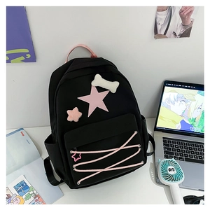 Detail of black student backpack with pink star and cross-lace ribbons on white desk