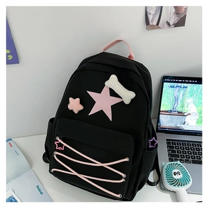 Close-up of black school backpack with pink star, cross straps and cute plush pins