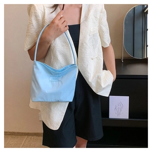 Detail of light blue nylon handbag featuring onwards and upwards embroidery on fabric
