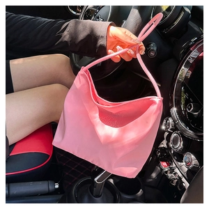 Pink nylon shoulder bag with embossed text detail shown inside a vehicle interior