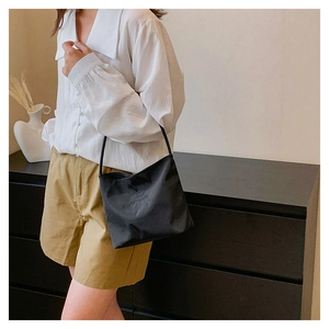 Detailed view of black nylon shoulder bag with embossed letters on a female model
