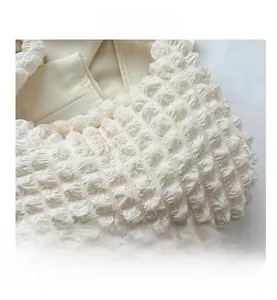 Detailed close-up of cream-white bubble textured fabric on a large capacity shoulder bag
