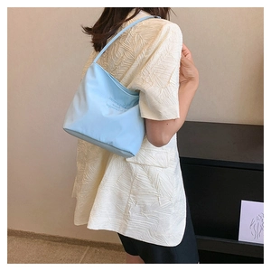 Close-up of light blue nylon bag with 'onwards and upwards' print worn by model