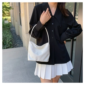Chic white nylon square handbag worn by model against a modern architectural wall background