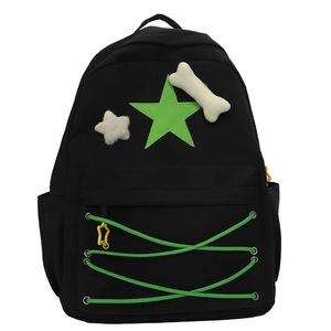 Detail view of black backpack with green star patches and fuzzy bone pendant