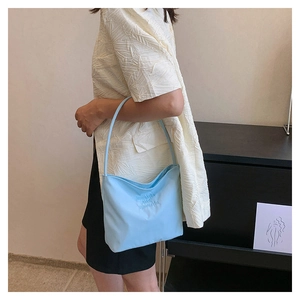 Detail of light blue nylon shoulder bag featuring onwards and upwards embossed lettering