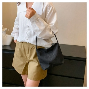 Close-up of black nylon shoulder bag styled with casual white shirt and khaki shorts