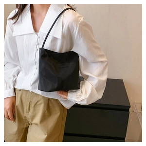 Detail of minimalist black nylon handbag with onward and upward embossed text and handle