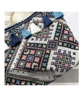 Detailed macro view of woven geometric patterns and colorful tassels on canvas tote bag