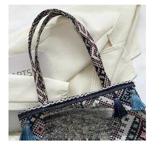 Detailed close-up of ethnic woven tote bag with geometric patterns and fringe charms