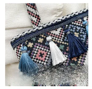 Close-up of ethnic geometric woven tote bag with colorful tassel and blue handle