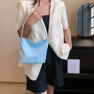 Light blue nylon underarm shoulder bag with embroidered text shown on a female model