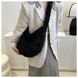 Detail of black popcorn texture cloud bag worn by a model in professional office attire