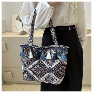 Detail of bohemian knit tote bag with colorful geometric patterns and blue tassels